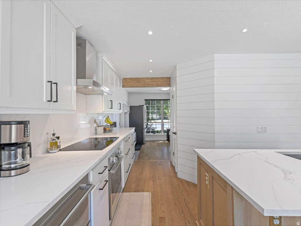 Modern kitchen featuring white shaker cabinetry, stainless steel appliances, and wood-finish flooring