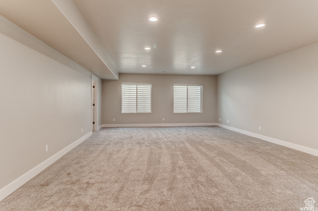 Spacious room featuring neutral carpeting, recessed lighting, and two windows with horizontal blinds