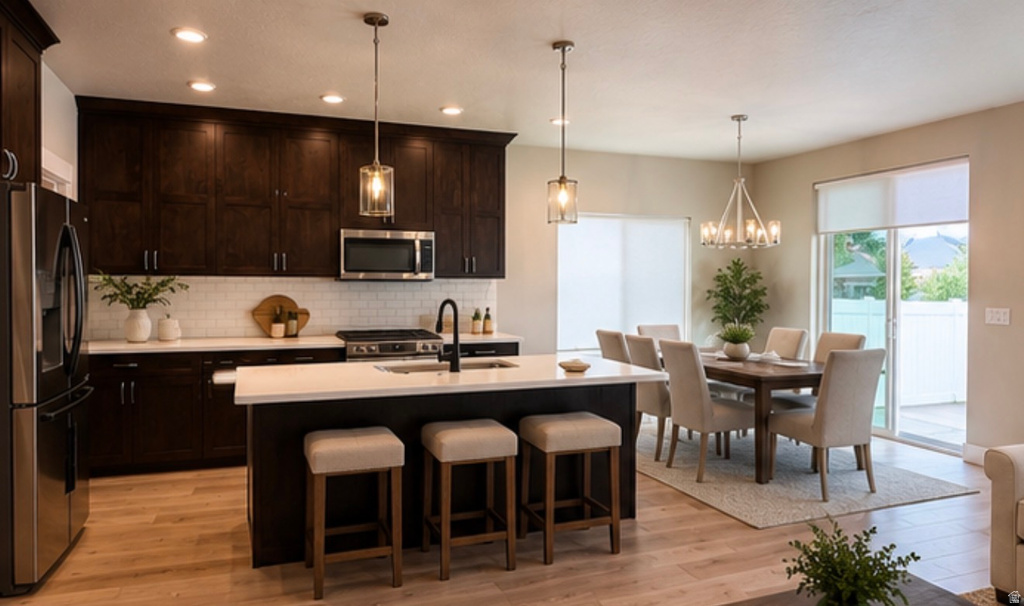 Kitchen featuring dark wood cabinetry, stainless steel appliances, a white subway tile backsplash, and a center island with counter seating