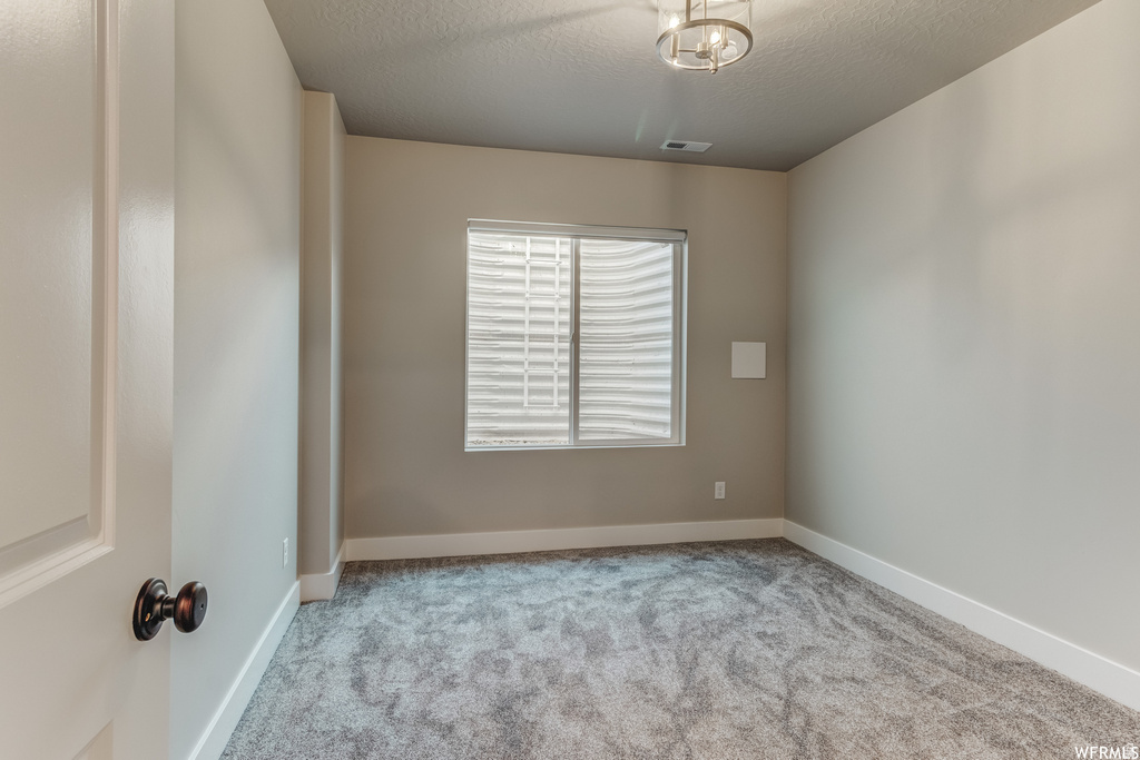 Neutral tone walls, gray carpet flooring, white trim, window with blinds, and a modern ceiling fixture