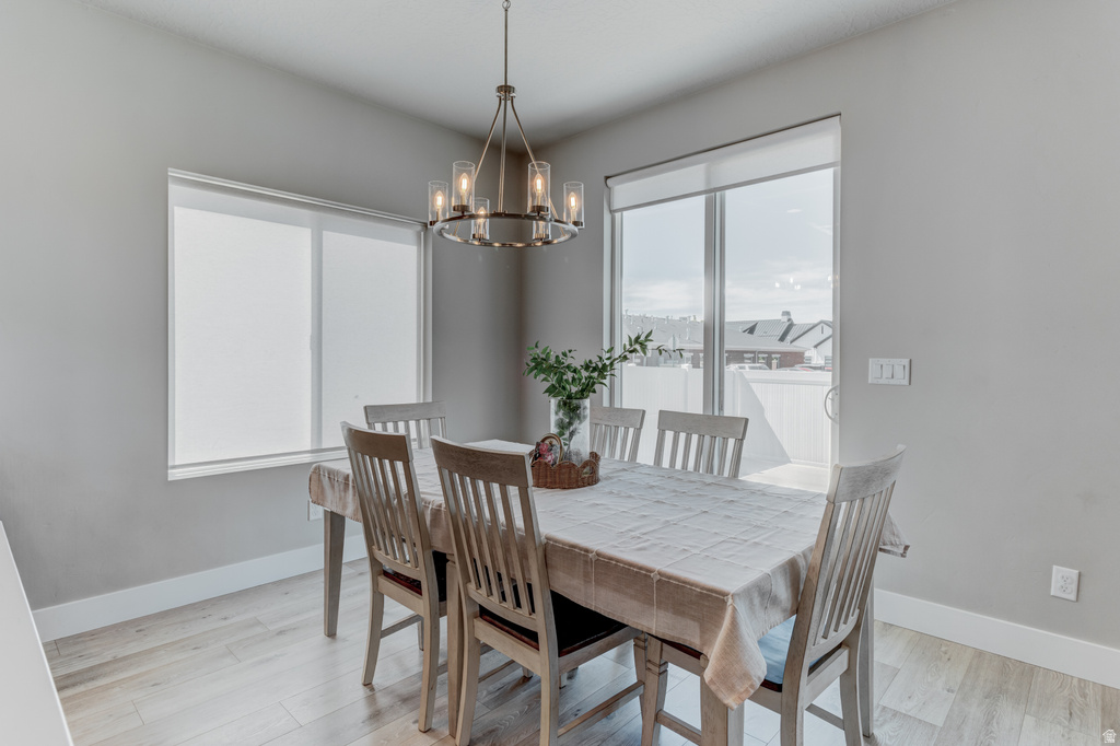 Dining area featuring light wood-finish flooring, a contemporary chandelier, a sliding glass door, and a large window