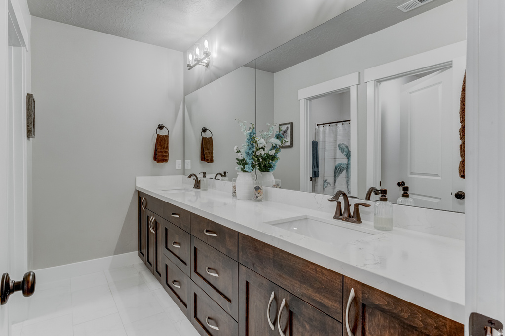 Dual vanity featuring white countertops, undermount sinks, and wood-finish cabinetry with brushed nickel hardware