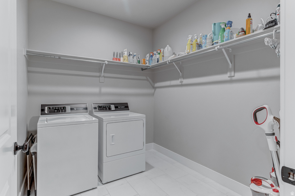 Dedicated laundry area featuring a washer and dryer, light gray wall paint, white trim, and white tile flooring