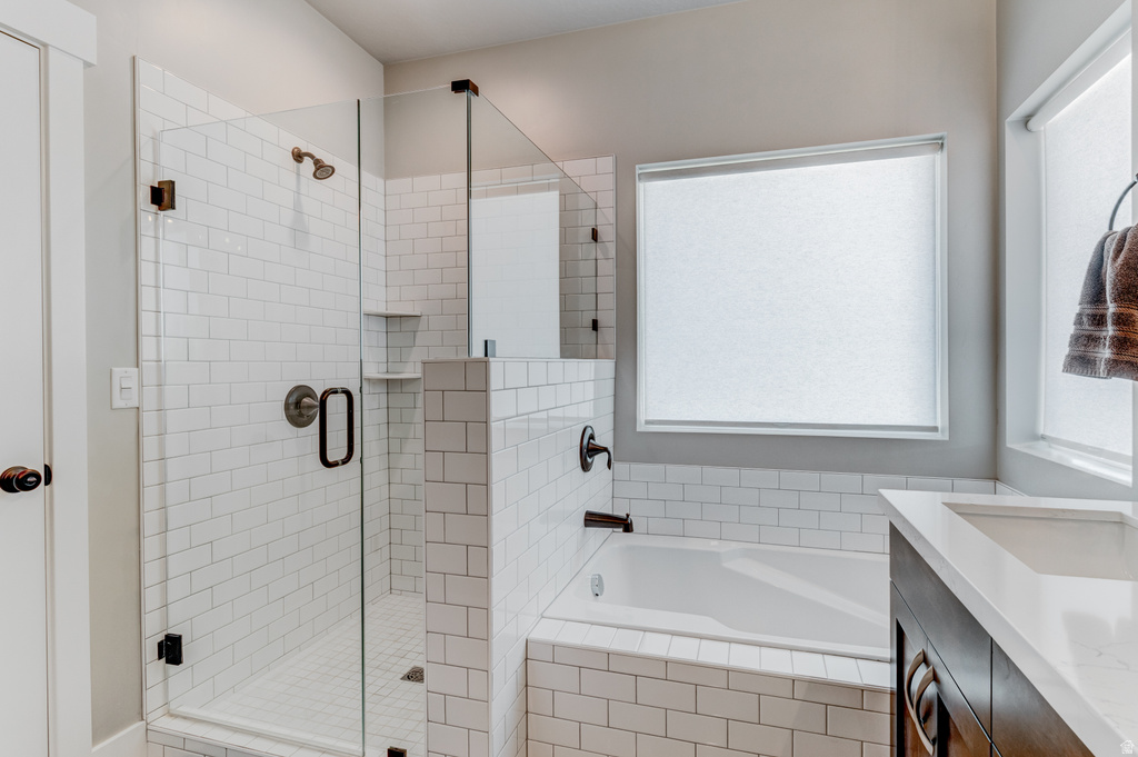 Contemporary bathroom featuring a glass-enclosed shower with subway tile surround and integrated shelving, a built-in bathtub with subway tile wainscoting, and a vanity with an integrated sink and quartz countertop