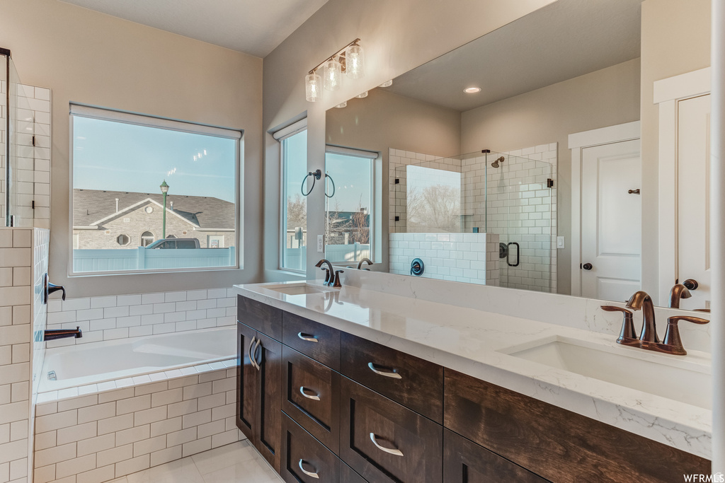 Dual vanity with integrated sinks and a large mirror, rich wood-finish cabinetry, a freestanding tub, and a separate shower with subway tile surround and clear glass enclosure