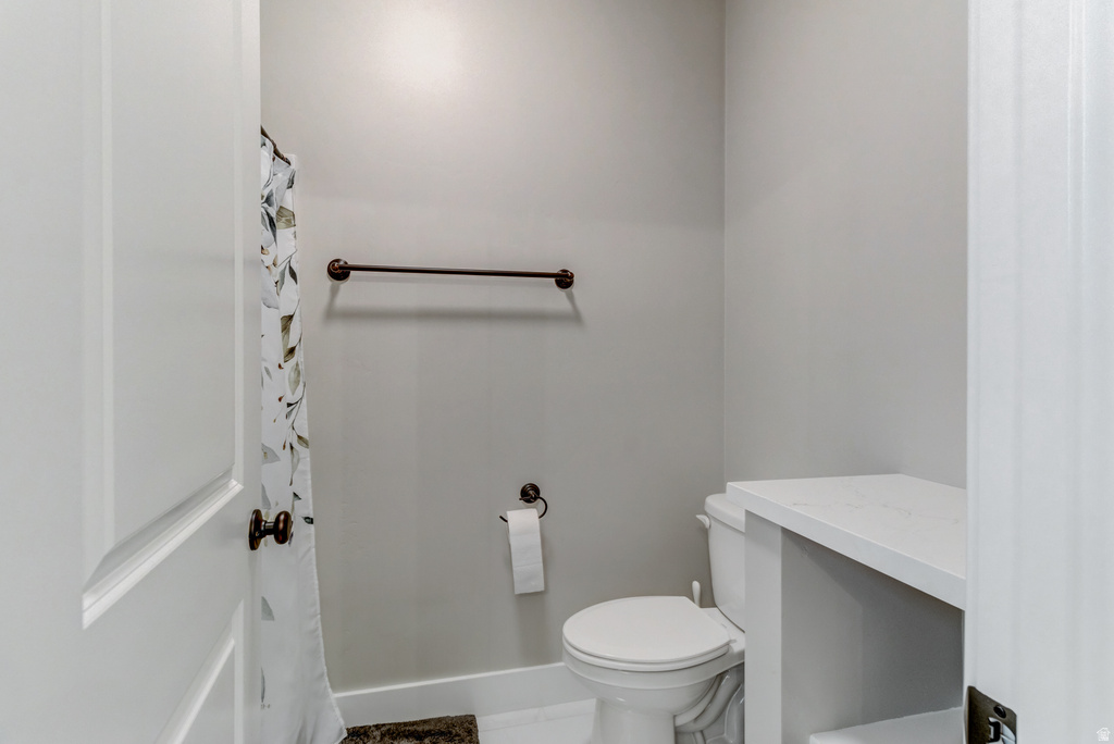 Modern bathroom featuring a white toilet, light gray walls, and a white countertop