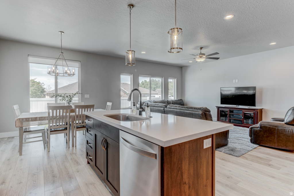 Open-concept living space featuring wood-finish flooring, a kitchen island with integrated sink, recessed lighting, and a ceiling fan