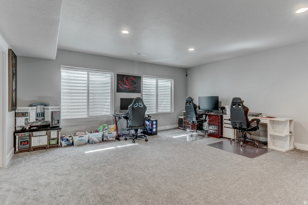 Spacious room featuring light gray carpeting, recessed lighting, and multiple egress windows with horizontal blinds