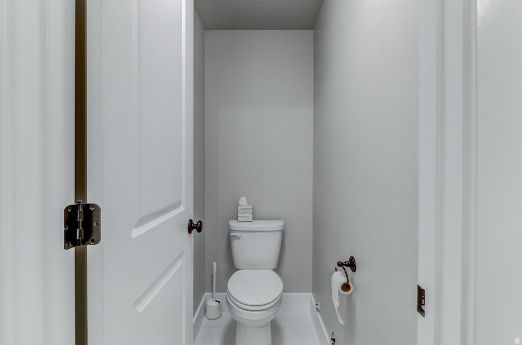 Compact powder room featuring a white toilet, light gray painted walls, and white baseboards