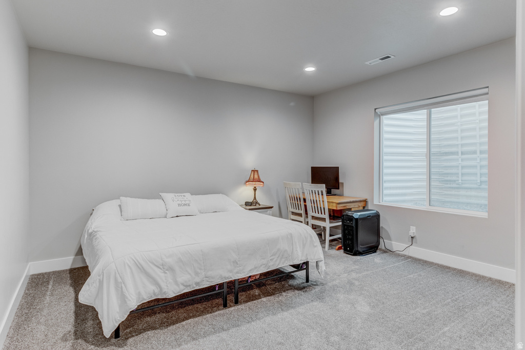 Spacious room featuring neutral grey wall paint, plush grey carpeting, recessed lighting, and a white-trimmed window
