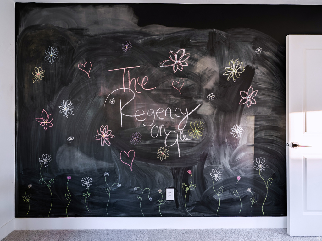 Chalkboard accent wall with white trim, featuring a contemporary door with a lever handle and plush gray carpeting
