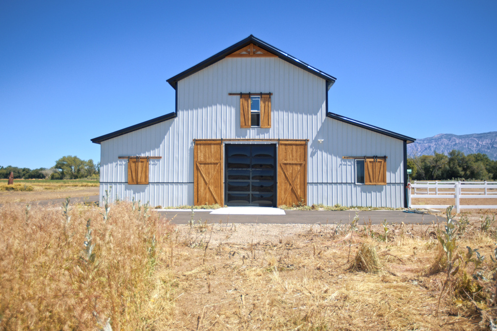 Modern barn-style structure featuring white corrugated metal siding, a black roof, and wood-finish sliding barn doors