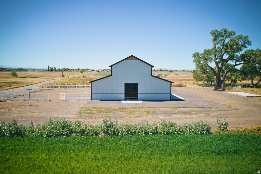 White barn structure featuring a black roof, black trim, and large black doors