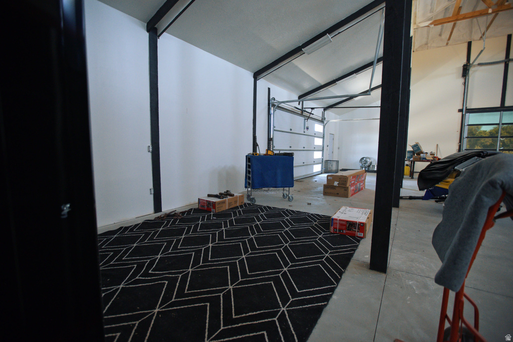 Spacious interior featuring a concrete floor, white walls, and exposed black structural beams
