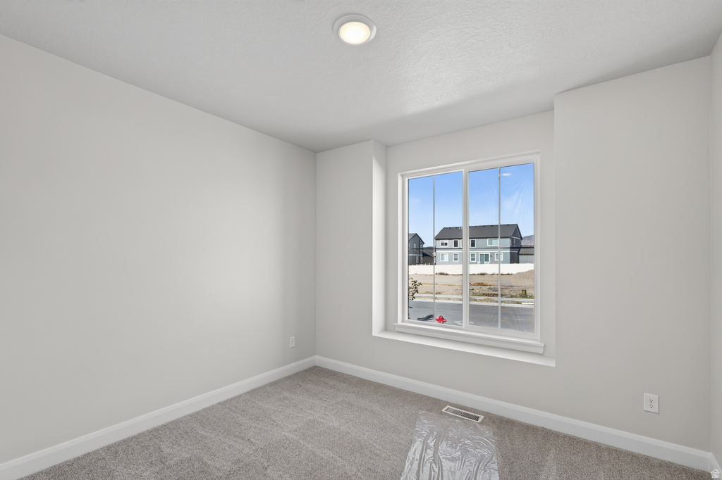 Neutral interior room featuring a large double-pane window, recessed ceiling lighting, light gray wall paint, white baseboards, and gray carpet flooring