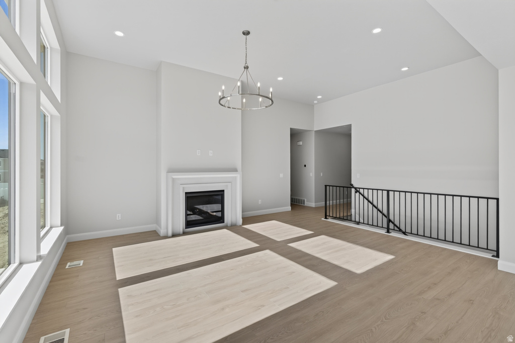 Spacious living area featuring high ceilings, wood-finish flooring, and a contemporary fireplace with a classic mantel