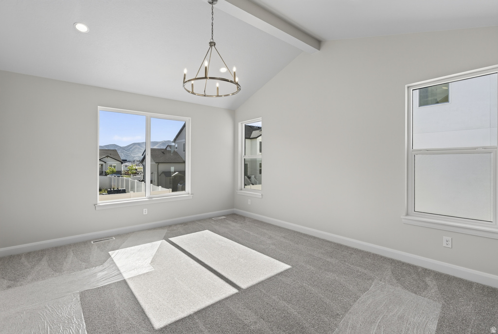 Vaulted ceiling with an exposed beam, a contemporary chandelier, recessed lighting, and multiple windows