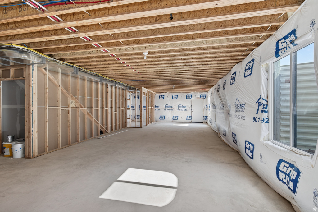 Unfinished basement with exposed wood joists and subfloor, offering an expansive concrete slab floor