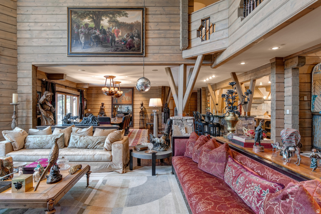 Great room featuring wood-plank walls, exposed structural beams, and a second-story open balcony with decorative railing