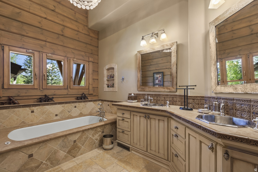 Bathroom featuring a built-in soaking tub with stone surround, wood-paneled walls, and a multi-window configuration