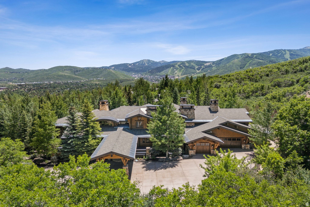 Expansive mountain property featuring a multi-level architectural design, wood siding, and multiple stone chimneys