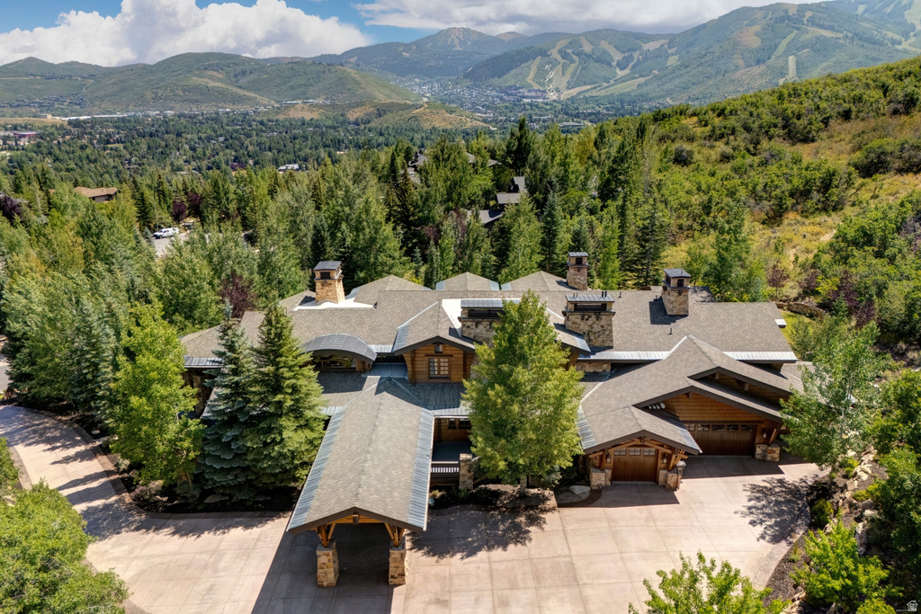 Expansive multi-level property featuring a stone and wood facade, multiple chimneys, an attached two-car garage, a porte-cochère, and a paver driveway