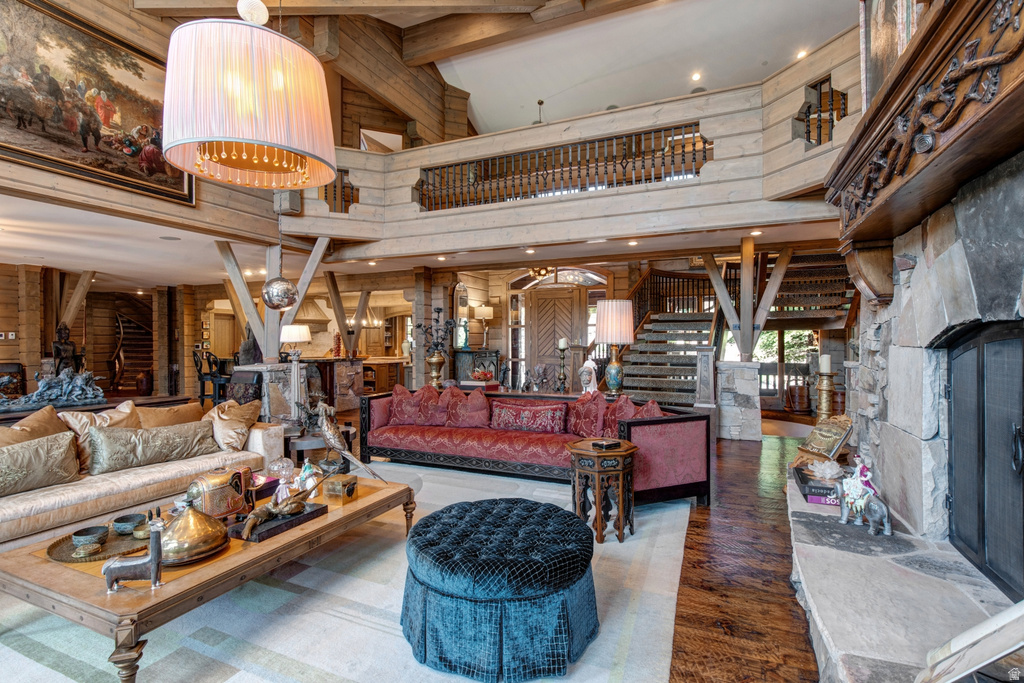 Spacious living area featuring a stone fireplace with a carved wood mantel, exposed wood beams, and a prominent chandelier