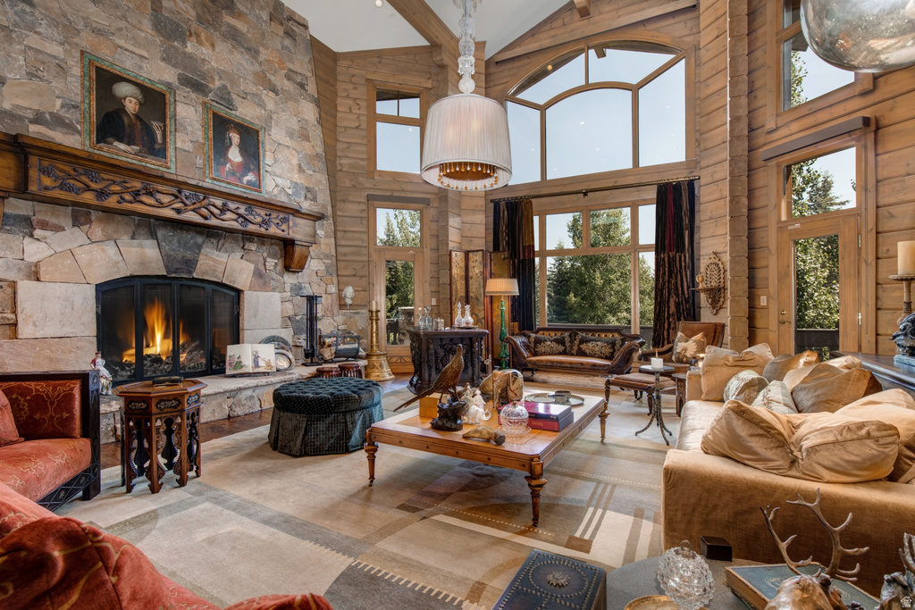Stone fireplace with an ornate wood mantel, high vaulted ceilings with wood beams, large picture windows, and wood-finish flooring