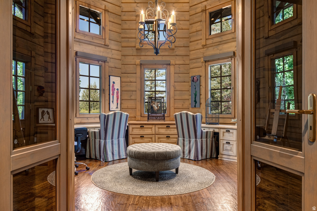 Paneled double doors open to a round room featuring extensive natural wood paneling, multiple windows, built-in cabinetry, and a wrought iron chandelier