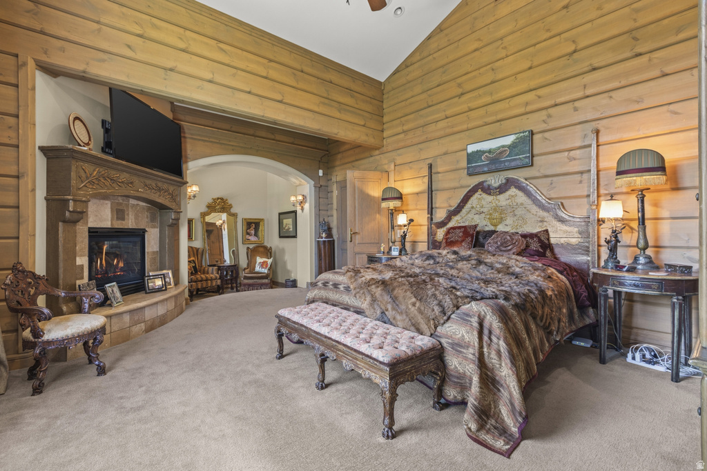 Wood-paneled room featuring a stone-clad fireplace with mantel, an arched entry, and vaulted ceilings