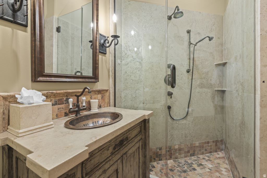 Bathroom featuring a rustic vanity with an oval vessel sink, a stone countertop, and a tiled backsplash