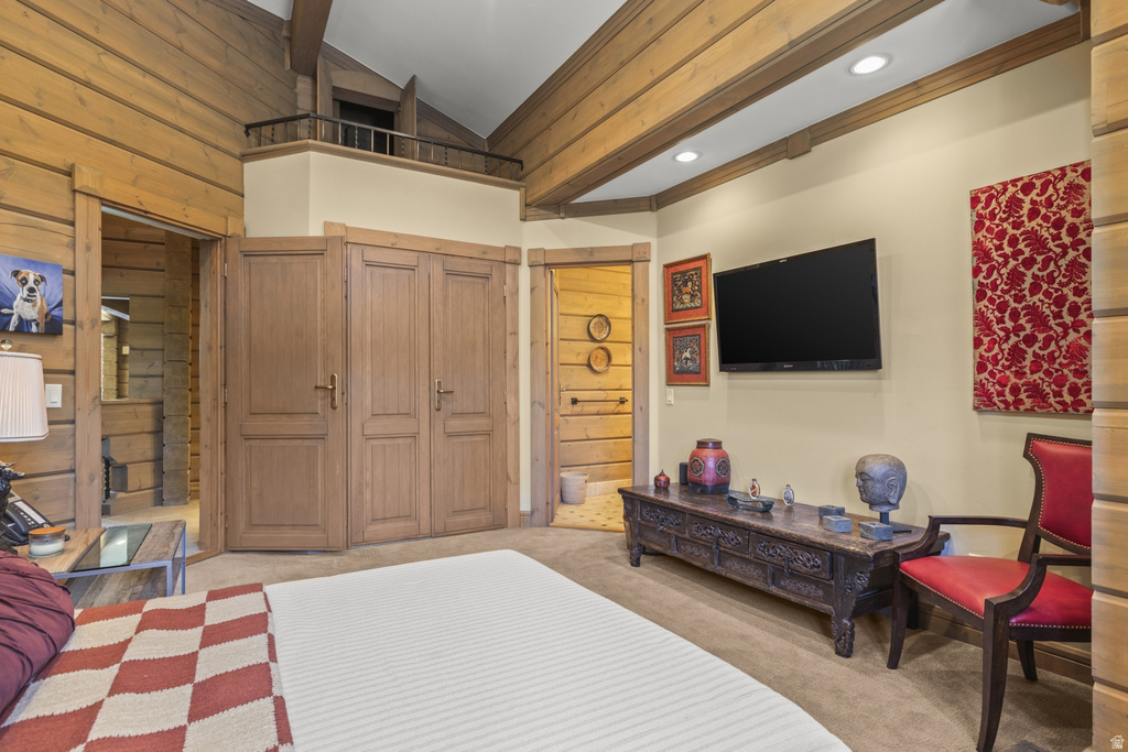 Exposed log walls featuring a vaulted ceiling with wood beams and recessed lighting