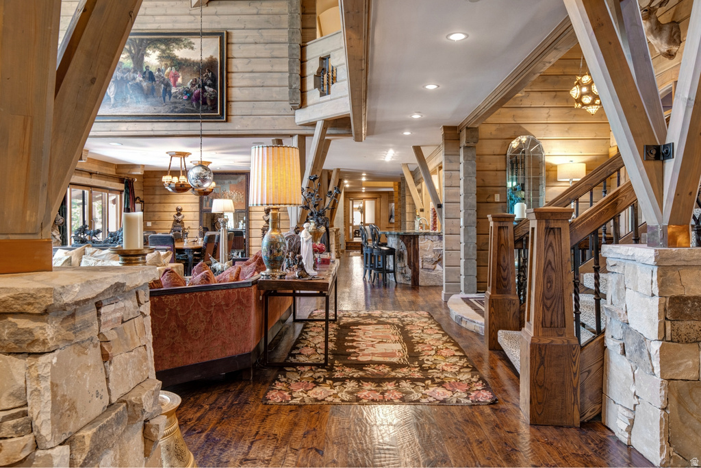 Spacious interior featuring wood-finish flooring, exposed wood beam construction, stone accents, and a built-in staircase with wrought iron balusters