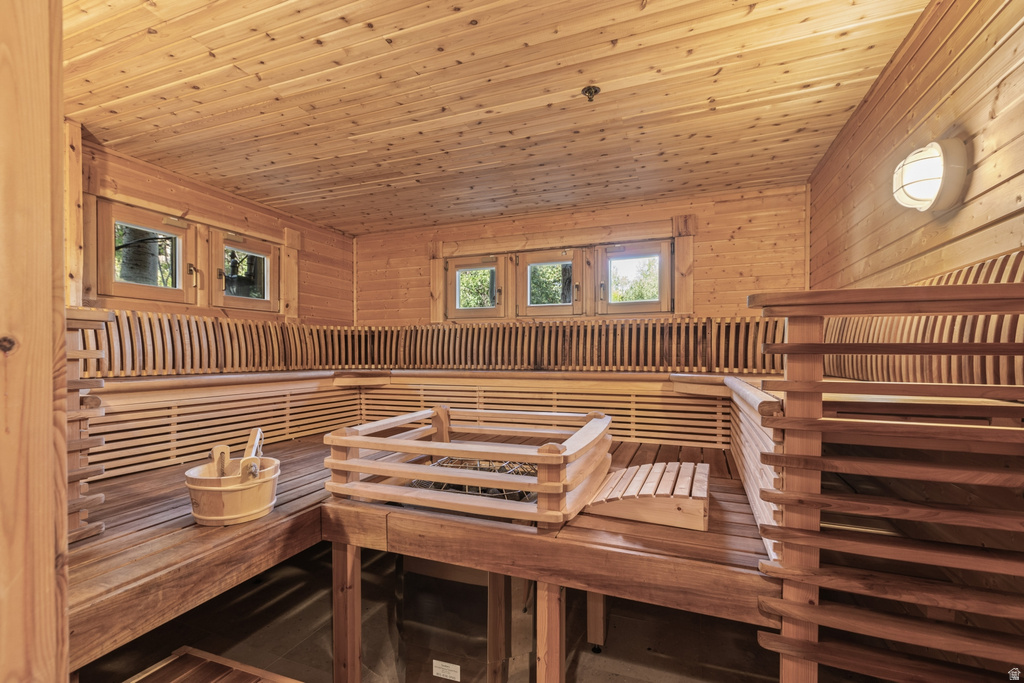 Dedicated sauna room featuring natural wood paneling throughout, multi-tiered bench seating, and a built-in heater with protective railing