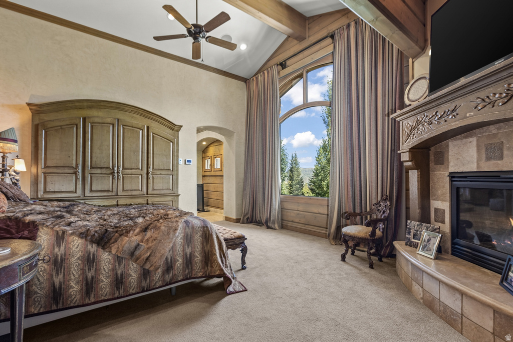 Vaulted ceilings with exposed wood beams, a stone-clad fireplace, and a large arched window