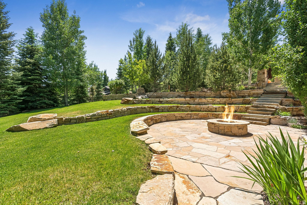 Tiered stone patio featuring a built-in fire pit, irregular flagstone paving, and stone retaining walls