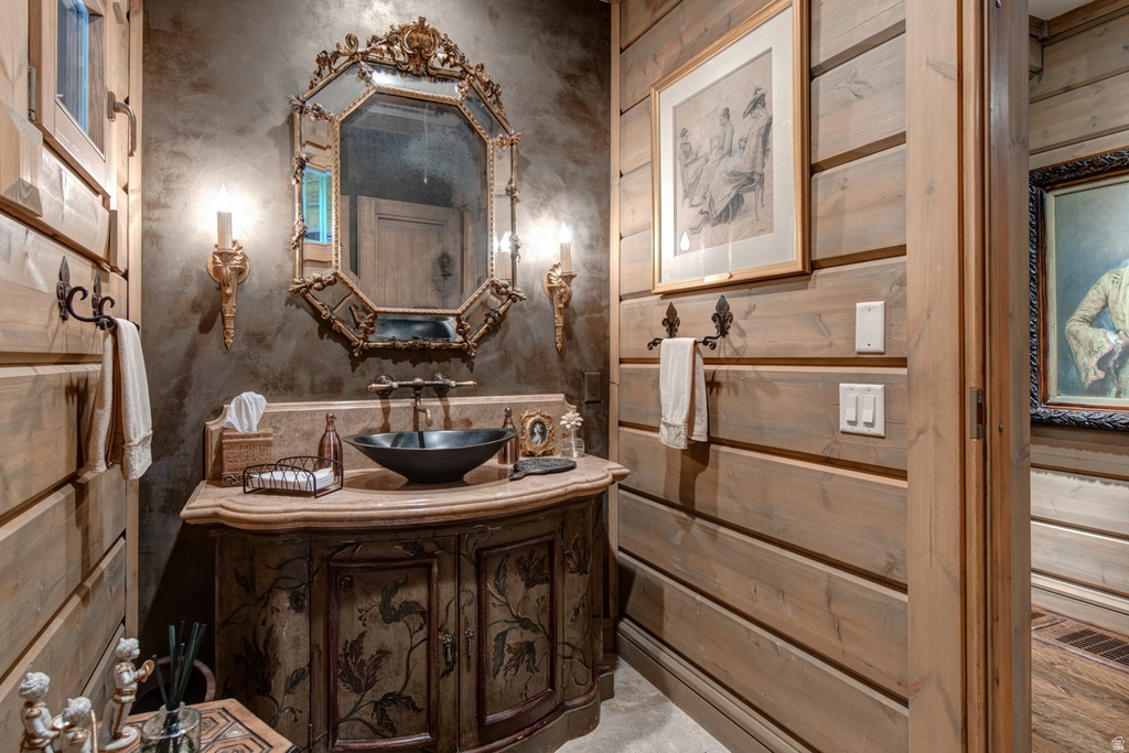 Vanity area featuring a decorative carved wood cabinet with a vessel sink and ornate framed mirror