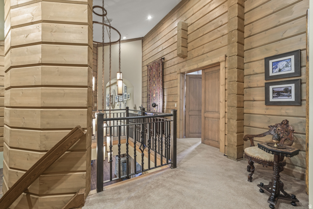 Stairwell featuring natural wood paneling, wood-finish staircase, wrought iron railing, and recessed lighting