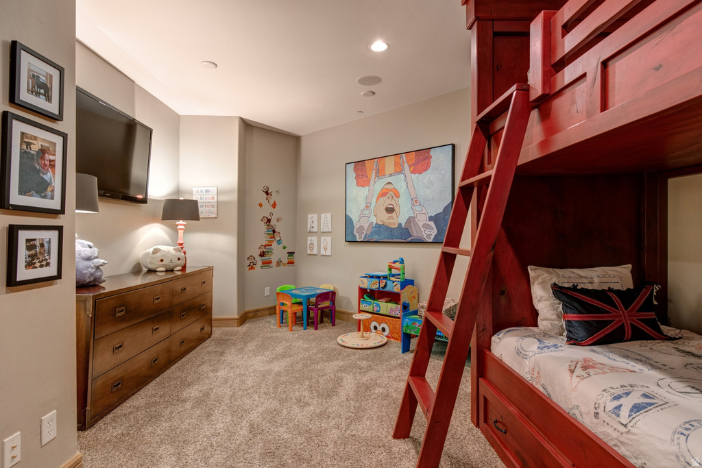 Built-in red bunk beds with integrated ladder and storage drawers, featuring recessed lighting, wall-mounted television, and wood-finish baseboards