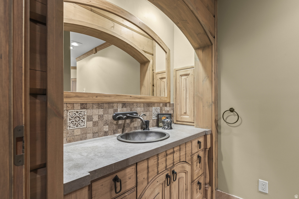 Custom wood vanity with distressed finish and black hardware, topped with a gray countertop and integrated circular sink
