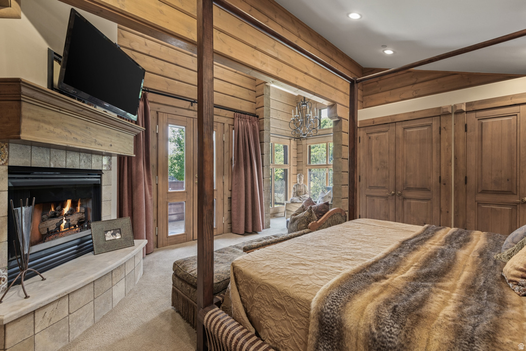 Bedroom featuring natural wood paneling and a tiled fireplace with a wood mantle