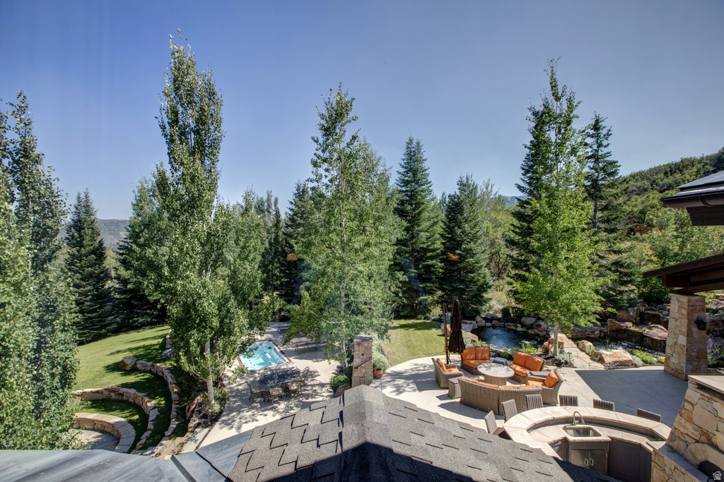 Expansive exterior featuring a stone patio, outdoor kitchen with sink, built-in fire pit, and a swimming pool