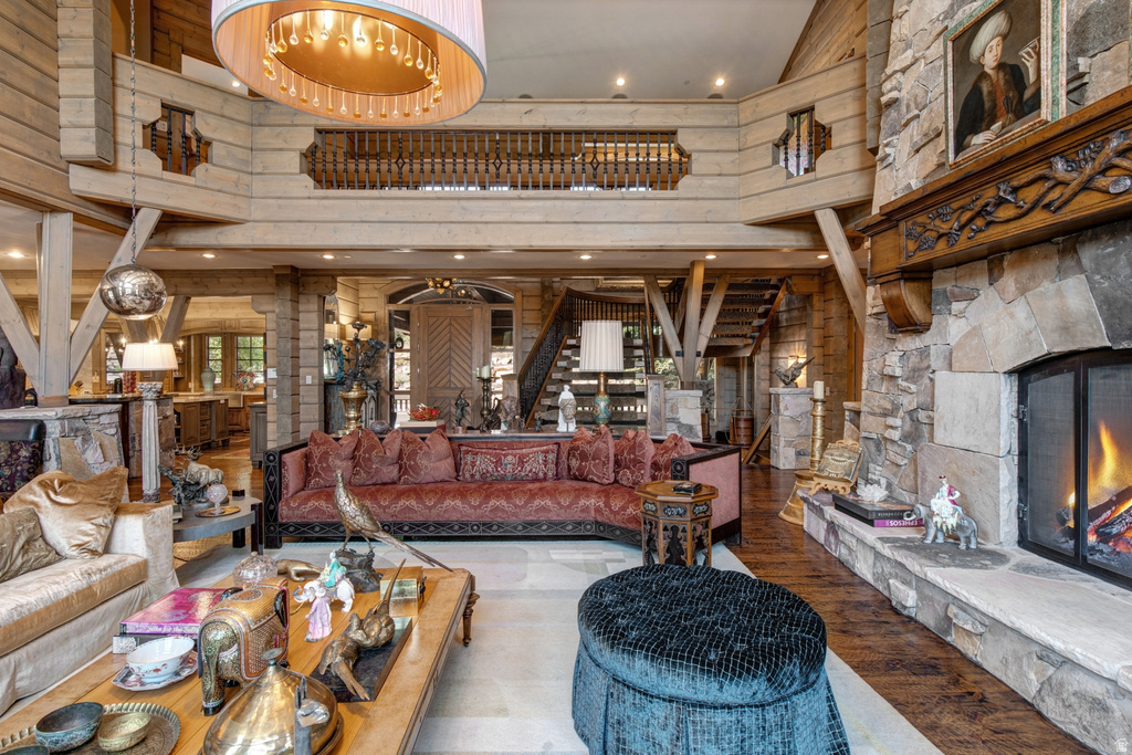 Spacious living area featuring a stone fireplace with a carved wood mantel, exposed wood beam ceiling, and a prominent chandelier