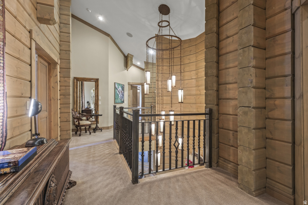 Second-story hallway featuring natural wood paneling, a detailed metal railing overlooking a lower level, and an elaborate multi-pendant light fixture