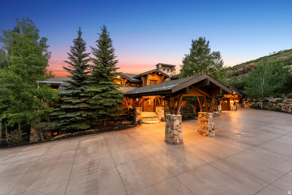 Mountain-style residence featuring a porte-cochère, a stone and wood exterior, and a concrete driveway