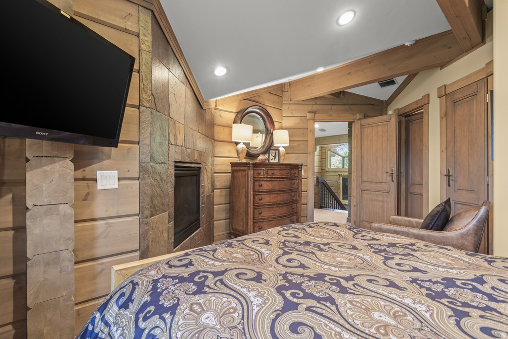 Stone accent wall with built-in fireplace, wood-planked walls, and exposed wood beams