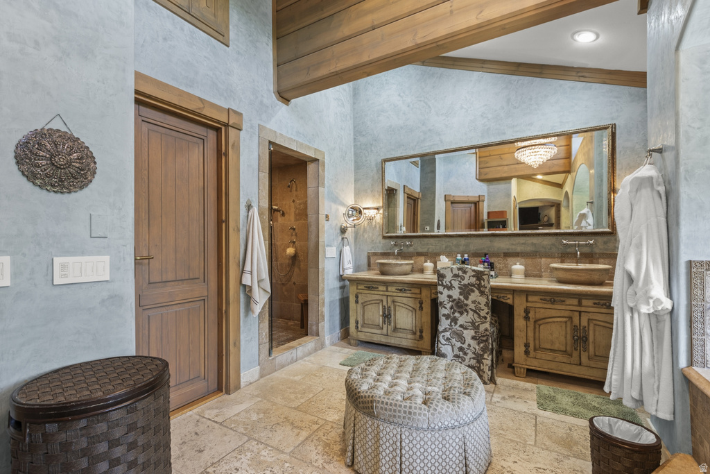 Spacious bathroom featuring a dual vanity with vessel sinks, a large mirror, a separate shower enclosure, and exposed wood ceiling beams