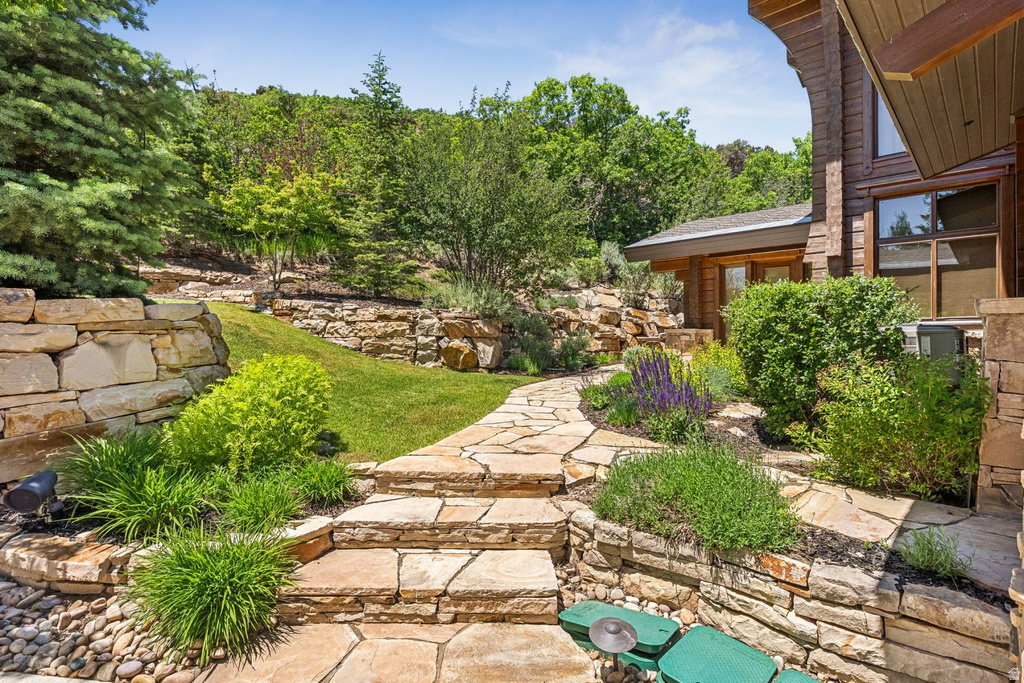 Terraced landscaping featuring natural stone retaining walls, flagstone pathways, and mature greenery