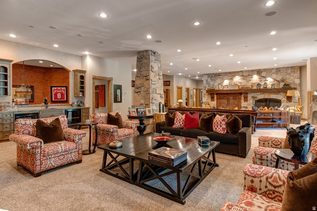 Spacious carpeted living area featuring a stone accent wall with a large built-in fireplace, a stone column, and recessed ceiling lighting