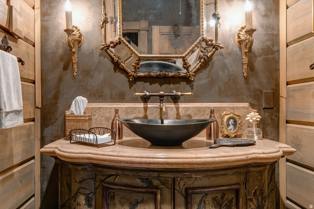 Custom vanity with a rounded stone countertop, black vessel sink, and an ornate gold-framed mirror